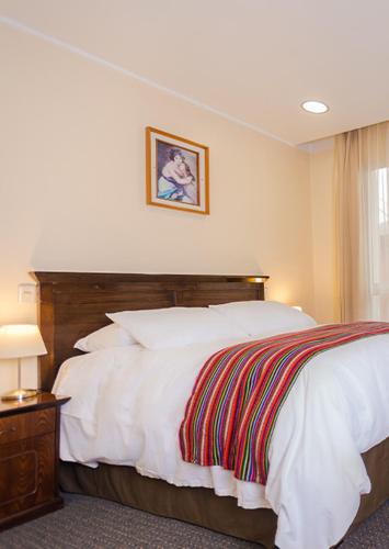 a bedroom with a white bed with a wooden headboard at Hotel de Turistas Huancayo - Hotel Asociado Casa Andina in Huancayo