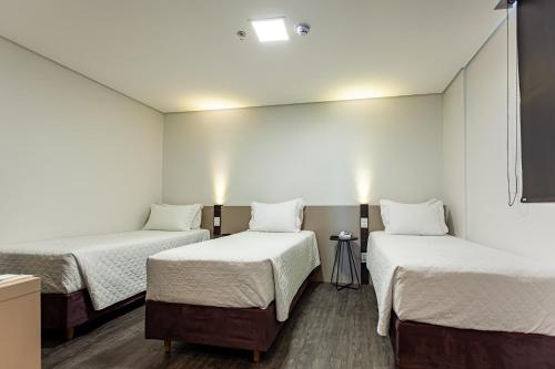 a room with three beds and a mirror at Travel Inn Hotels Caxias do Sul in Caxias do Sul