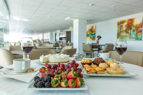 a table with two plates of food and glasses of wine at Travel Inn Hotels Caxias do Sul in Caxias do Sul