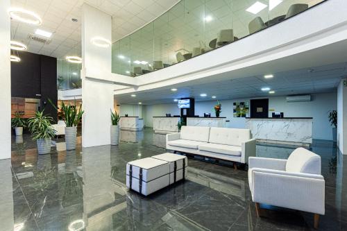 a lobby with white couches and chairs in a building at Travel Inn Hotels Caxias do Sul in Caxias do Sul