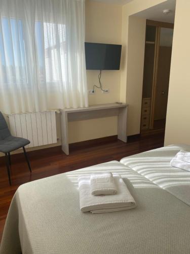 a bedroom with two beds and a tv on the wall at Posada H.El Alba in Boó de Piélagos
