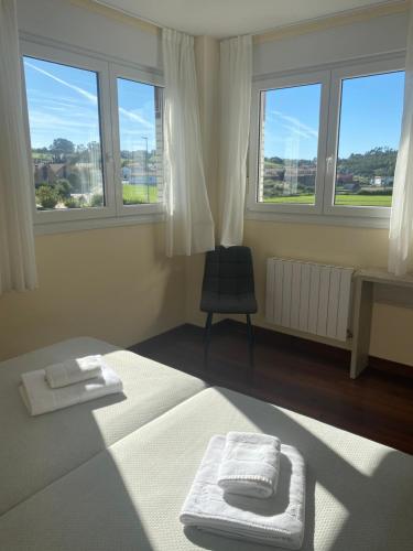 a room with a bed and a chair and windows at Posada H.El Alba in Boó de Piélagos