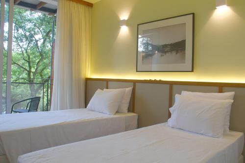 two beds in a room with a window at Hotel Porto do Ribeirão in Iporanga