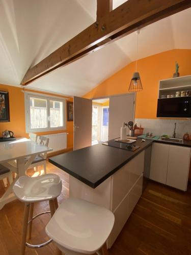 una cucina con piano di lavoro nero e sgabelli bianchi di Le Loft brestois a Brest