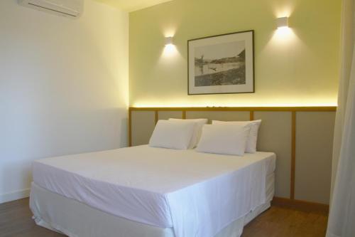 a bedroom with a white bed with two white pillows at Hotel Porto do Ribeirão in Iporanga
