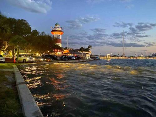 a lighthouse with cars parked next to a body of water at New Pics! Harbour Town 3BR/3BA - Pool Access - Book Now in Hilton Head Island