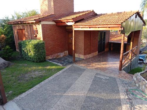 una casa de ladrillo con un camino que conduce al patio delantero en Cabañas Layken en Villa Carlos Paz