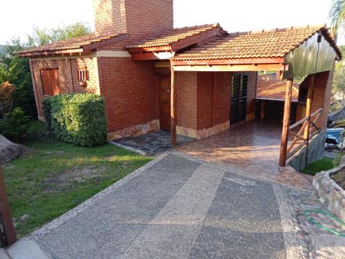 a brick house with a pathway leading into the front yard at Cabañas Layken in Villa Carlos Paz