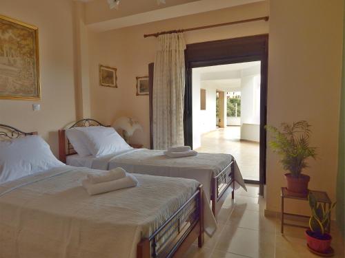 a bedroom with two beds and a door to a patio at ΟΔΥΣΣΕΙΑ, κοντά σε αεροδρόμιο, λιμάνια και θάλασσες in Keratea