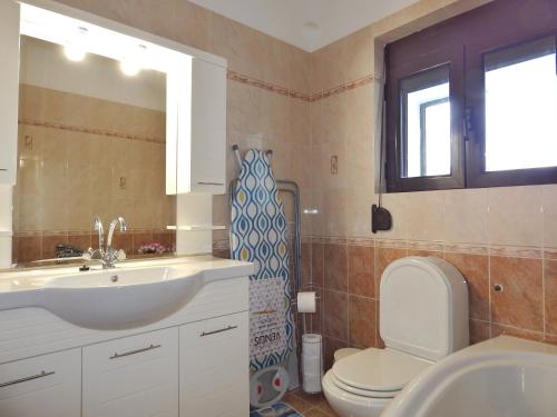 a bathroom with a sink and a toilet and a window at ΟΔΥΣΣΕΙΑ, κοντά σε αεροδρόμιο, λιμάνια και θάλασσες in Keratea