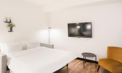 a white bedroom with a bed and a chair at Radisson Blu 1882 Hotel, Barcelona Sagrada Familia in Barcelona