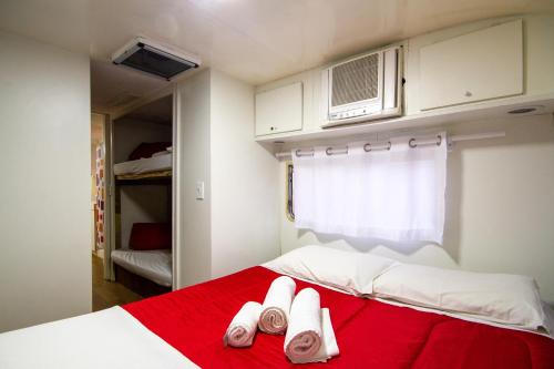 a bedroom with a red bed with two pairs of slippers at Villa Vintage Campos - Piscina e opções de suites com hidromassagem in Campos do Jordão