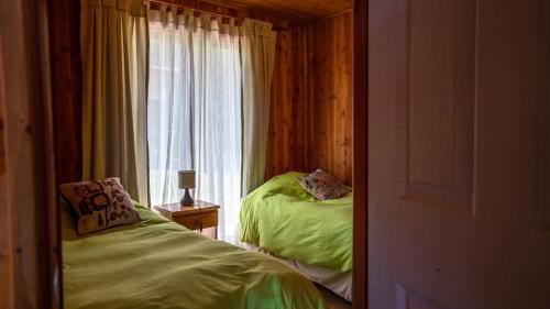 a bedroom with two beds and a window at Cabañas Copayapu in Pucón
