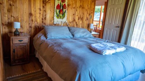 a bedroom with a blue bed with a wooden wall at Cabañas Copayapu in Pucón