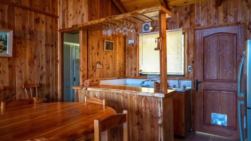 a kitchen with wooden walls and a table and a sink at Cabañas Copayapu in Pucón