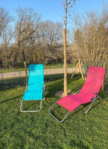 two chairs sitting in the grass next to a fence at Agimon'TOIT in Hastière-par-delà