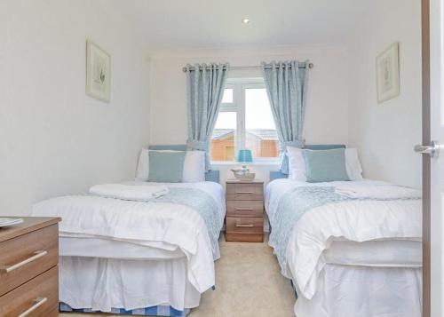 a bedroom with two twin beds and a window at Cherry Tree Lodge in Narberth