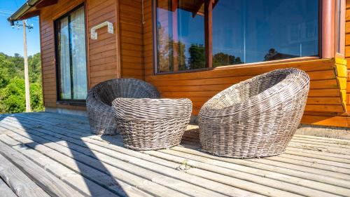 two wicker chairs sitting on the front of a house at Cabañas Copayapu in Pucón