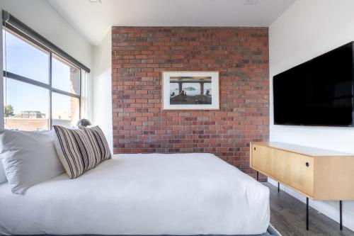 a bedroom with a white bed and a brick wall at Reside Seattle Downtown, a Wyndham Residence in Seattle