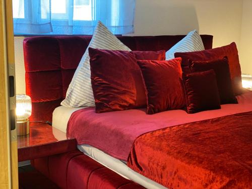 - un lit rouge avec de nombreux oreillers dans l'établissement FeWo Souterrain TT-Bodensee, à Tettnang