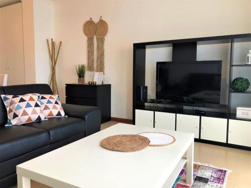 a living room with a black couch and a tv at Apartamento Mar com Parking in Nazaré