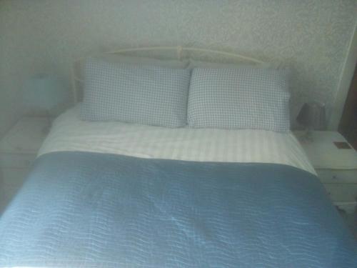 uma cama com lençóis e almofadas azuis e brancos em Welsh Homestay em Cardiff