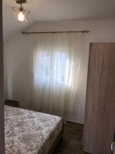 a bedroom with a bed and a window at Apartmani Vanja in Baošići