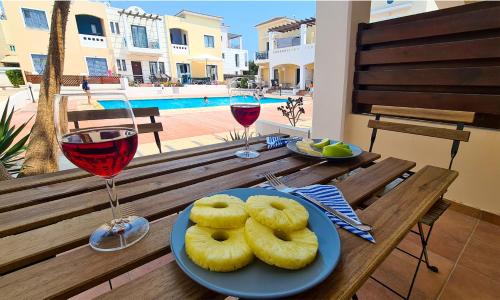 a table with two plates of food and glasses of wine at Maria's Holiday House - Communal Pool in Paphos City