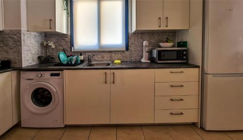 a kitchen with a sink and a washing machine at Maria's Holiday House - Communal Pool in Paphos City