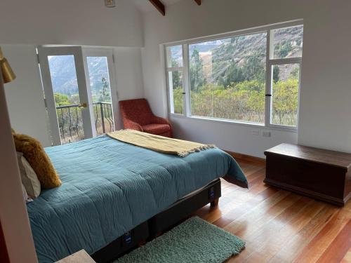 a bedroom with a bed and two large windows at AUKA VILLAS BOUTIQUE in Urubamba
