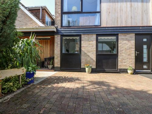 a brick house with black doors and a patio at Little Beach House in St Austell