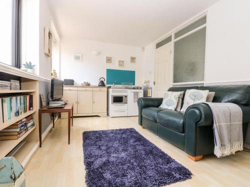 a living room with a green couch and a kitchen at Little Beach House in St Austell