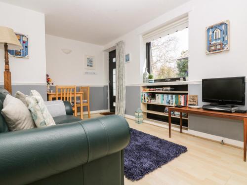 a living room with a couch and a tv at Little Beach House in St Austell