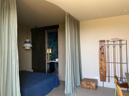 a bedroom with a blue bed and curtains and a table at Residenza Rosso Di Sera in Capoliveri