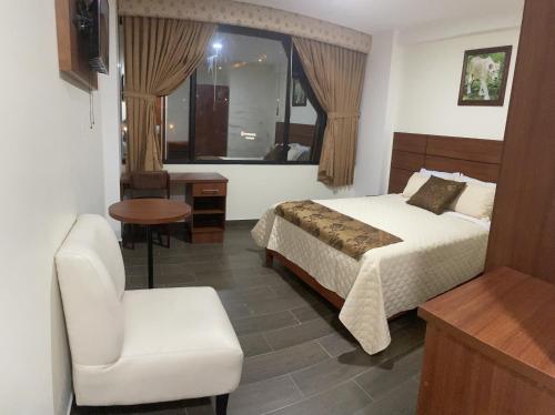 a hotel room with a bed and a chair at Hotel Dubai Ambato in Ambato