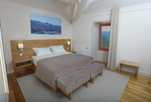 a bedroom with a large bed and a large window at Quinta da Riba Má in Santa Leocádia