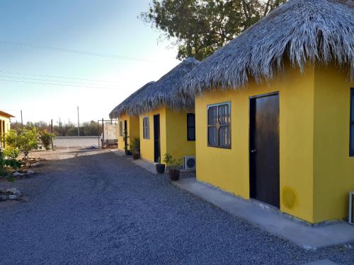 eine Reihe gelber Häuser mit einem Strohdach in der Unterkunft Loreto La Regional in Loreto