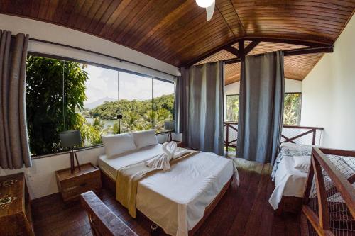 a bedroom with a bed and a large window at Pousada e Restaurante Mangue Seco Angra in Angra dos Reis