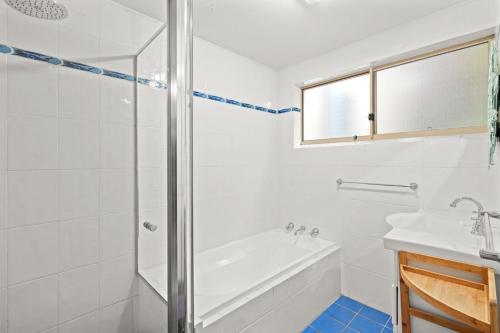 a white bathroom with a tub and a sink at Cosy Beachside Unit, Short Stroll to the Beach in Terrigal