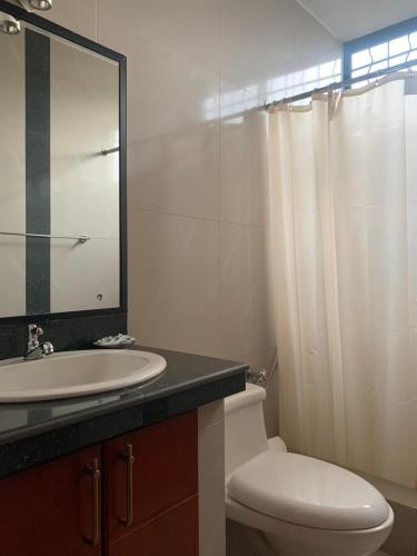 a bathroom with a sink and a toilet and a mirror at Hoteles en Guayaquil - Suites Guayaquil Cerca del Aeropuerto in Guayaquil