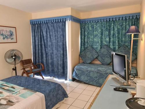 a hotel room with a bed and a desk with a television at Studio dans Résidence Hotelière aux 3ilets Pointe du bout Résidence la Marina Carayou in Les Trois-Îlets