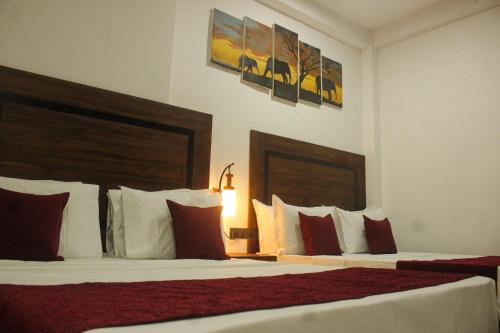 Cette chambre comprend 2 lits avec des oreillers rouges et blancs. dans l'établissement Divine Villa, à Anurâdhapura