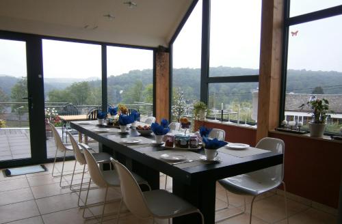 a long table with white chairs in a room with windows at B&B Le Bouchat-Oreille in Spontin