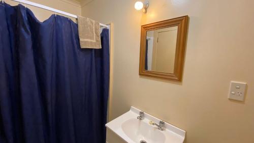 a bathroom with a blue shower curtain and a sink at National Park Backpackers in National Park