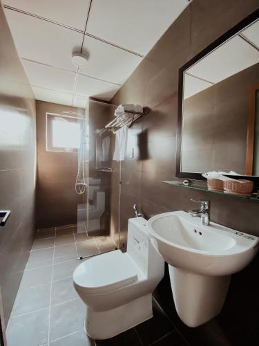 a bathroom with a toilet and a sink and a mirror at Khách sạn Ngọc Hồi in Quy Nhon