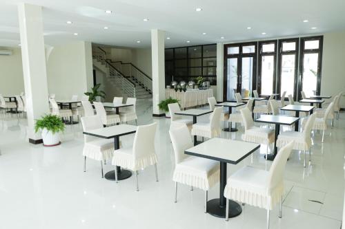 um restaurante com mesas brancas e cadeiras brancas em Crystal City Hotel em Mataram