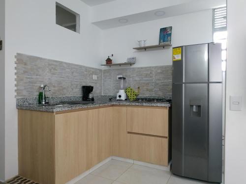 eine Küche mit einem Kühlschrank aus Edelstahl und Holzschränken in der Unterkunft APARTAMENTO LIVING en La CEJA in La Ceja