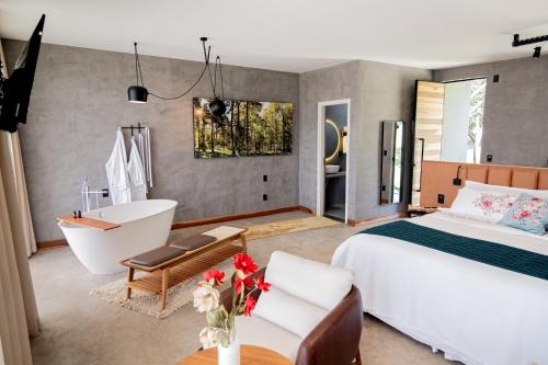 Schlafzimmer mit einem Bett, einer Badewanne und einer Badewanne in der Unterkunft Fazenda Pedra Lisa Hotel Boutique in Brumadinho