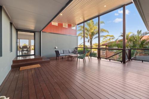 a house with a deck with a couch and chairs at Wahgunyah Road 52 in Nelson Bay