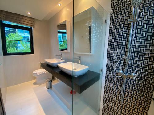 ein Badezimmer mit zwei Waschbecken und einer Glasdusche in der Unterkunft 360 Degree Kamala Seaview Villa in Kamala Beach